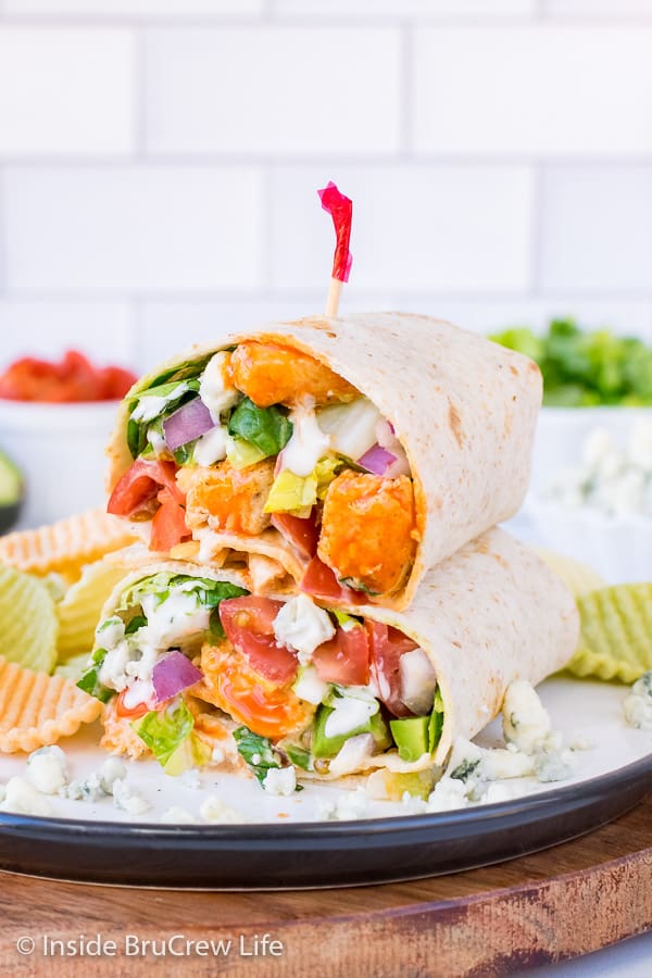 A buffalo chicken wrap loaded with veggies, cheese, and dressing cut in half and stacked on a plate
