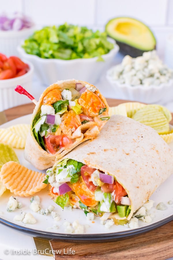 A buffalo chicken wrap cut in half and stacked on a plate showing the ingredients inside it.