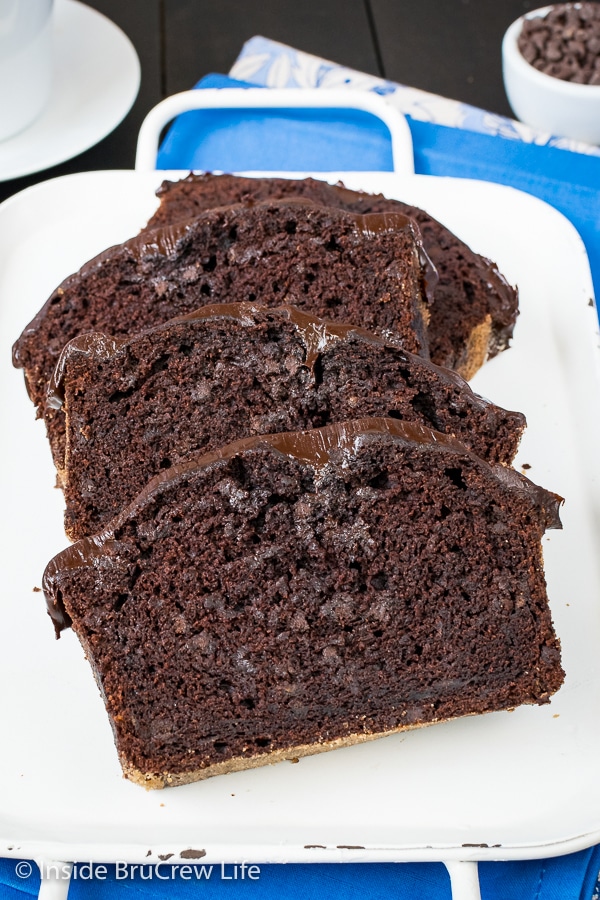Slices of frosted chocolate banana bread lying on a white tray.