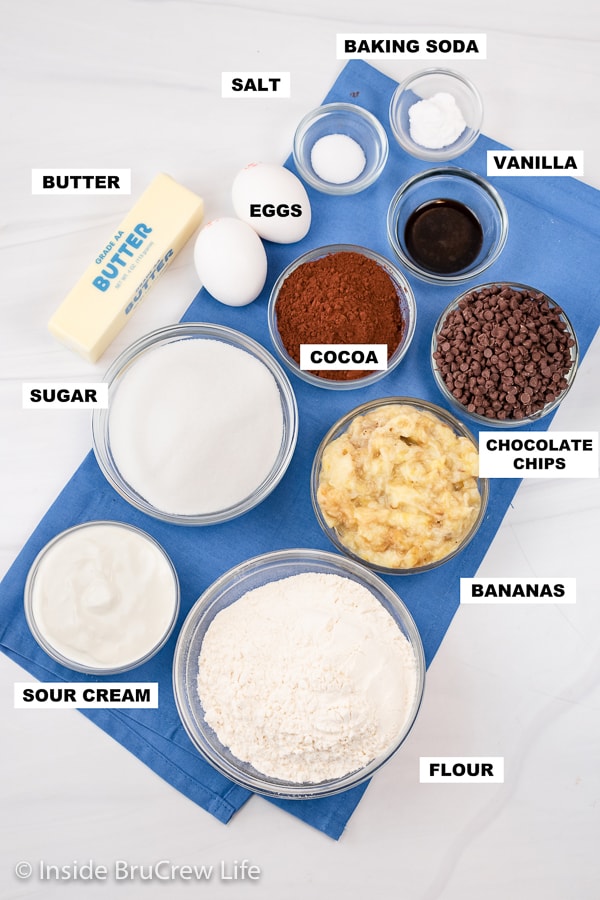 A white board with bowls of ingredients needed to make a banana bread with chocolate.