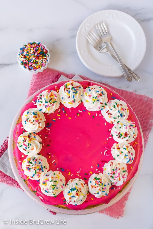 Funfetti Cheesecake - the hot pink white chocolate glaze and lots of sprinkles makes this cake batter cheesecake an impressive dessert. Great recipe to make for every celebration. #cheesecake #funfetti #cakebatter #sprinkles