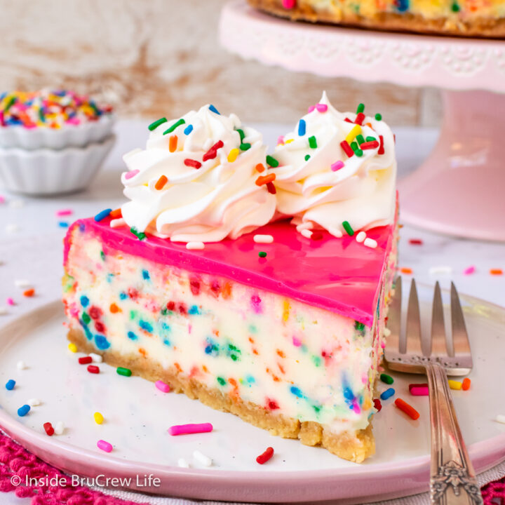 A slice of sprinkle dessert with pink chocolate on a plate.