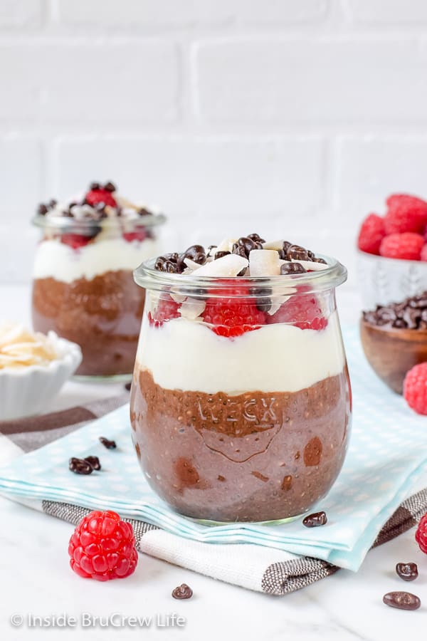 Two jars filled with a mocha coconut chia seed pudding and topped with yogurt and raspberries.