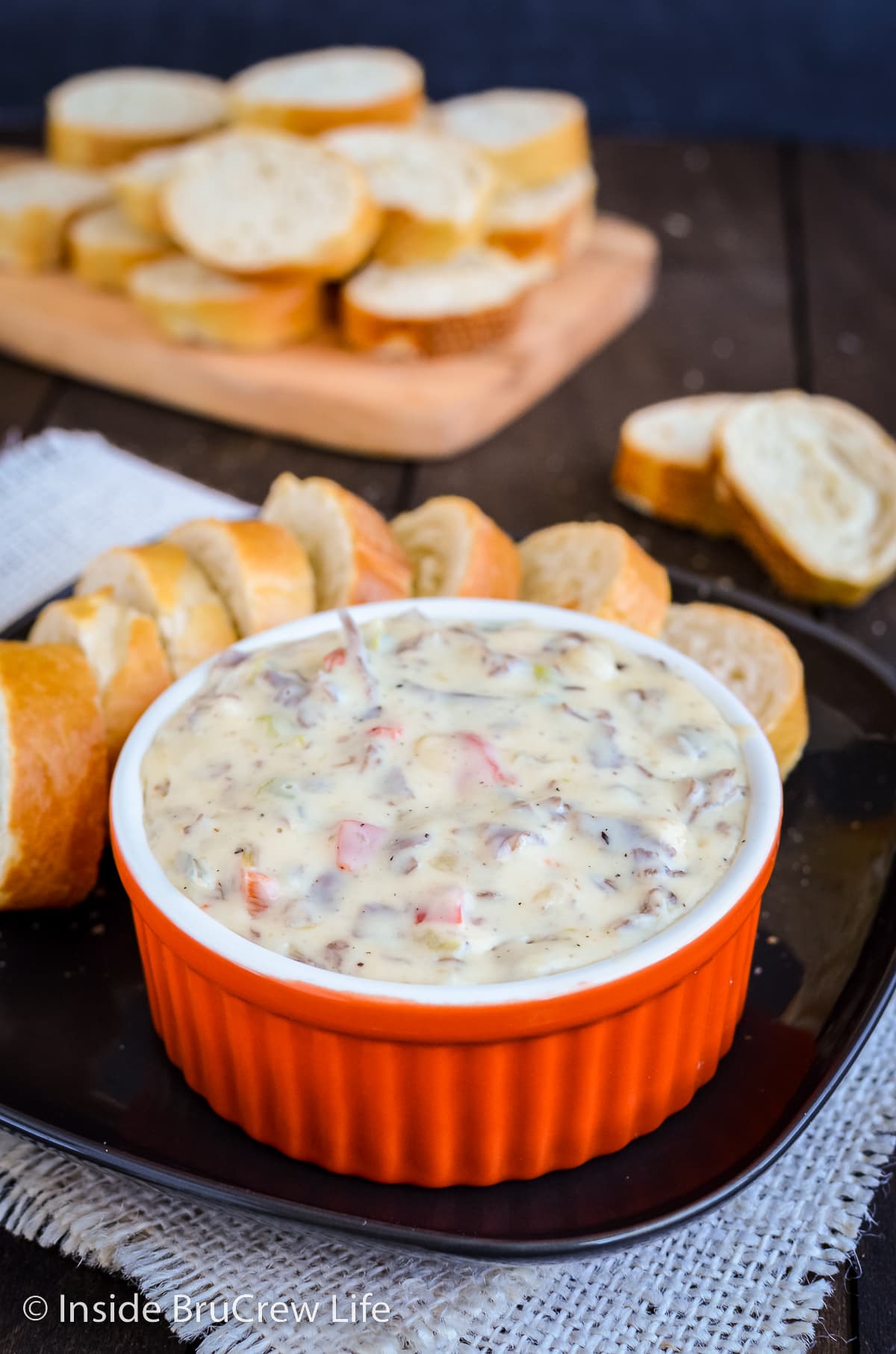 A bowl of Philly cheesesteak on a plate with baguette slices.