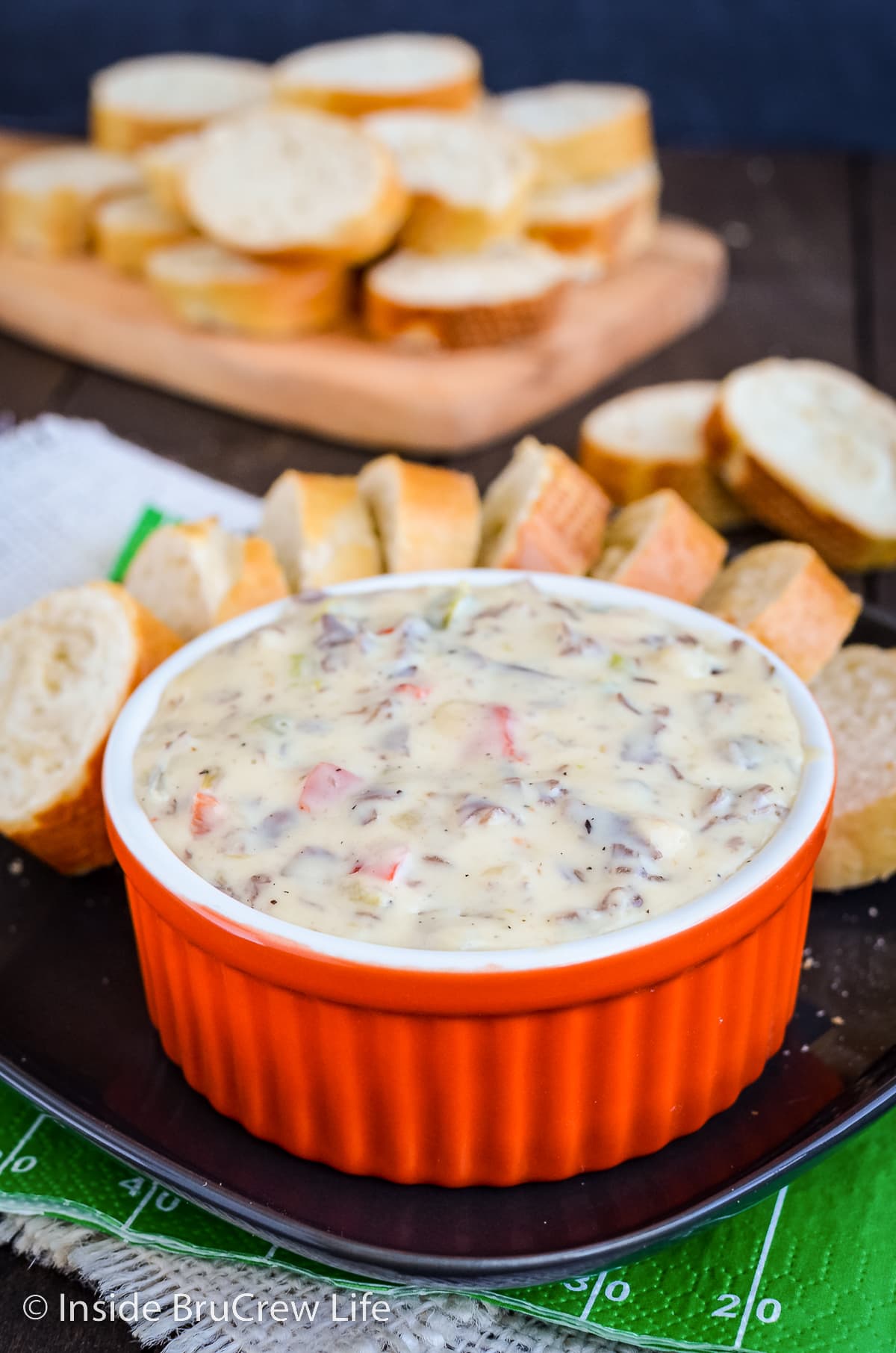 A bowl of Philly cheesesteak on a plate with baguette slices.