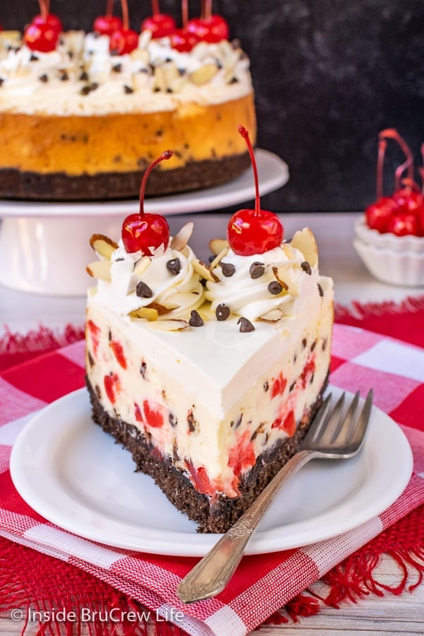 A slice of cherry almond cheesecake on a white plate.