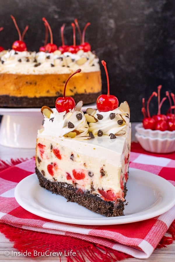 A slice of chocolate chip cherry cheesecake on a white plate.
