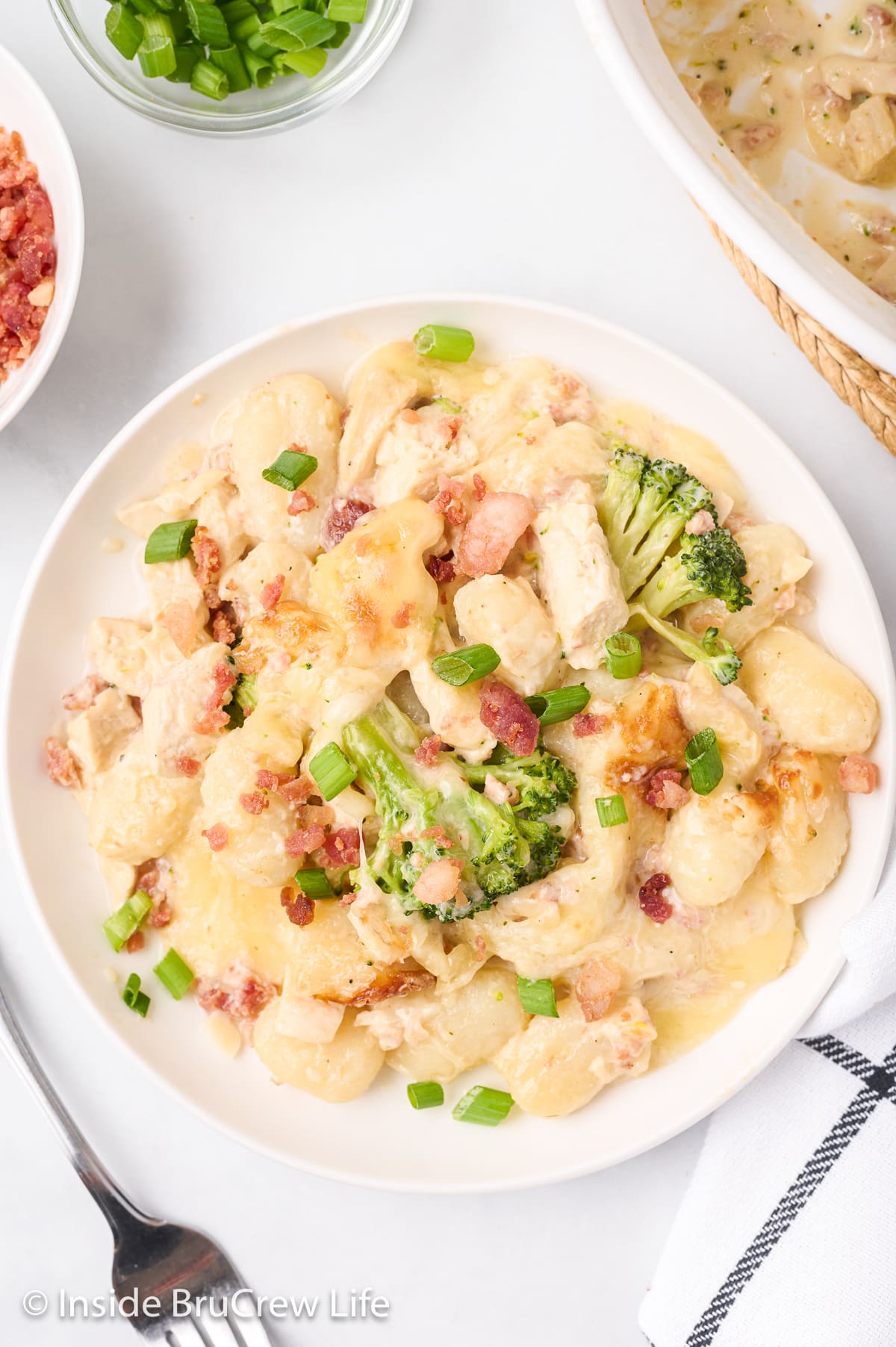 Baked gnocchi with chicken and broccoli on a white plate.