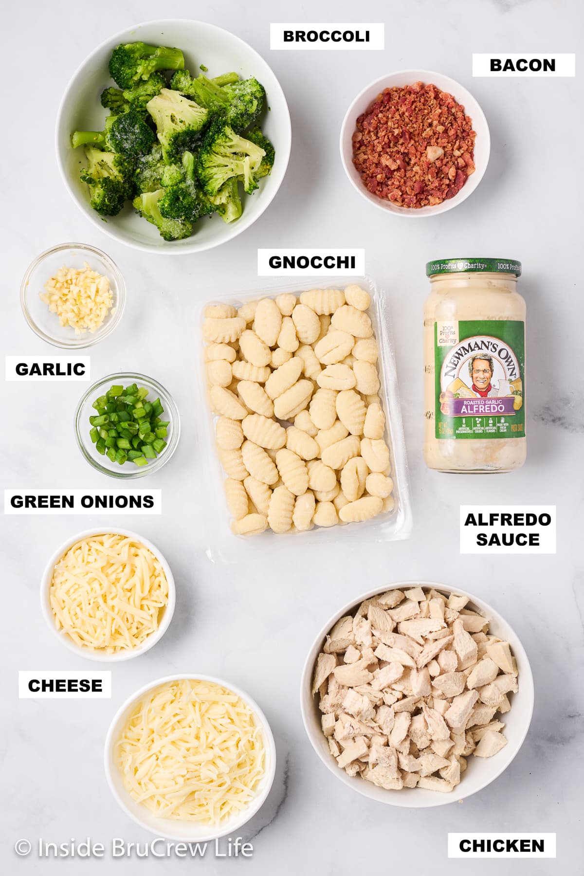 A white board with bowls of ingredients needed to make Alfredo gnocchi.