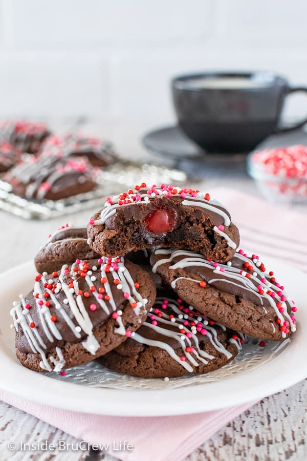 A white plate with chocolate cookies with red, pink, and white sprinkles.