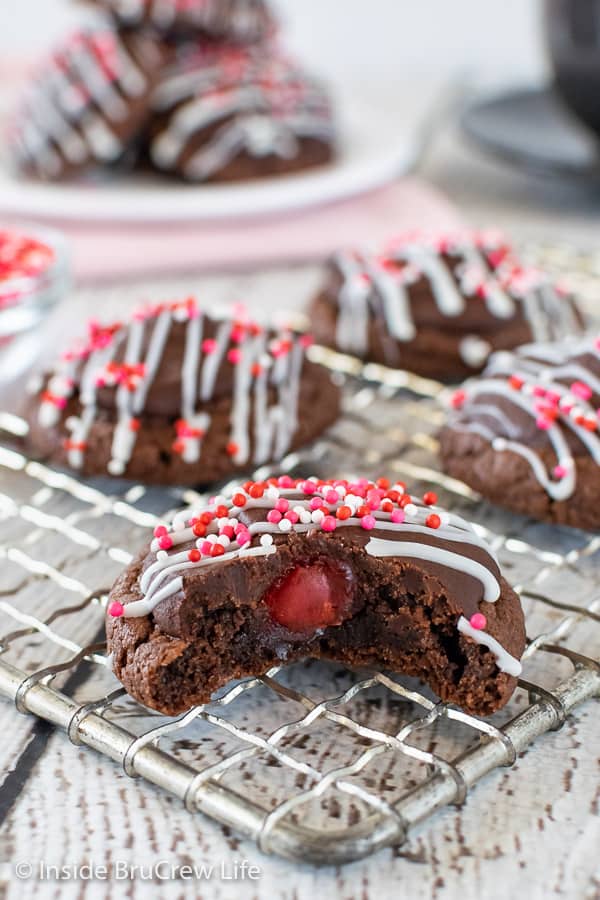 A chocolate cherry cookie with a bite out of it on a wire rack.