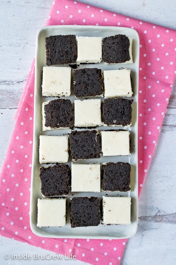 Multiple pieces of white coconut fudge with an oreo cookie base on a white plate.