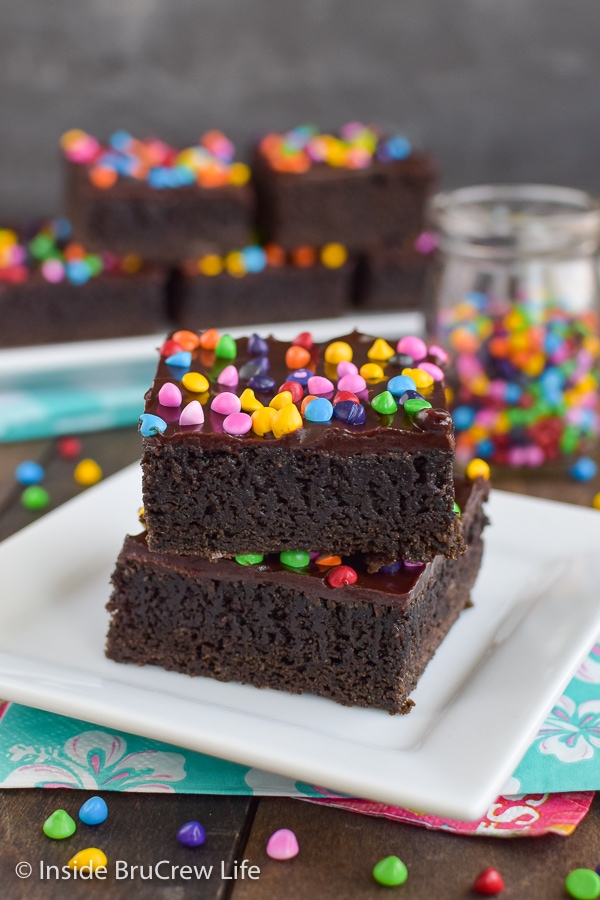 Two brownies on a white plate stacked on top of each other.