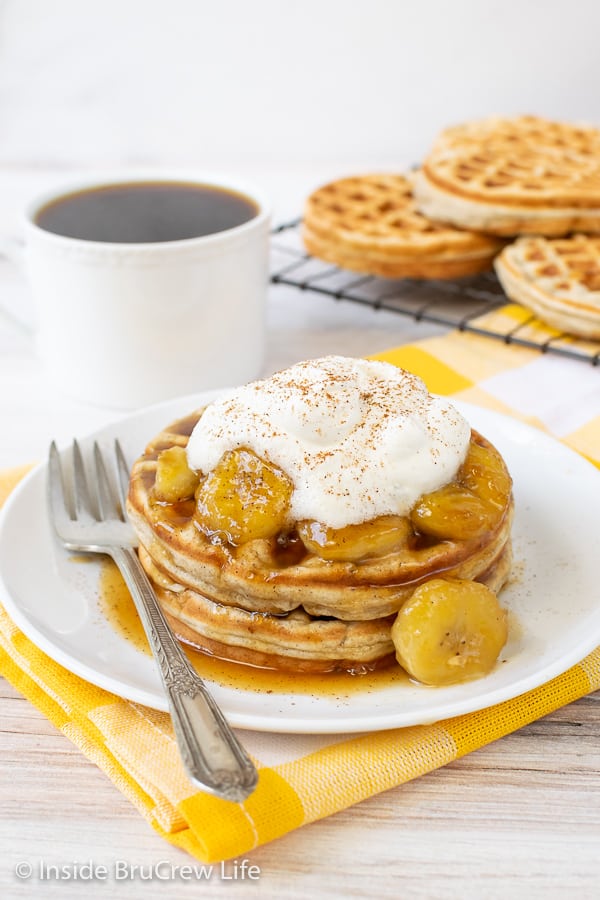 A white plate on a yellow towel with banana waffles and banana slices on it