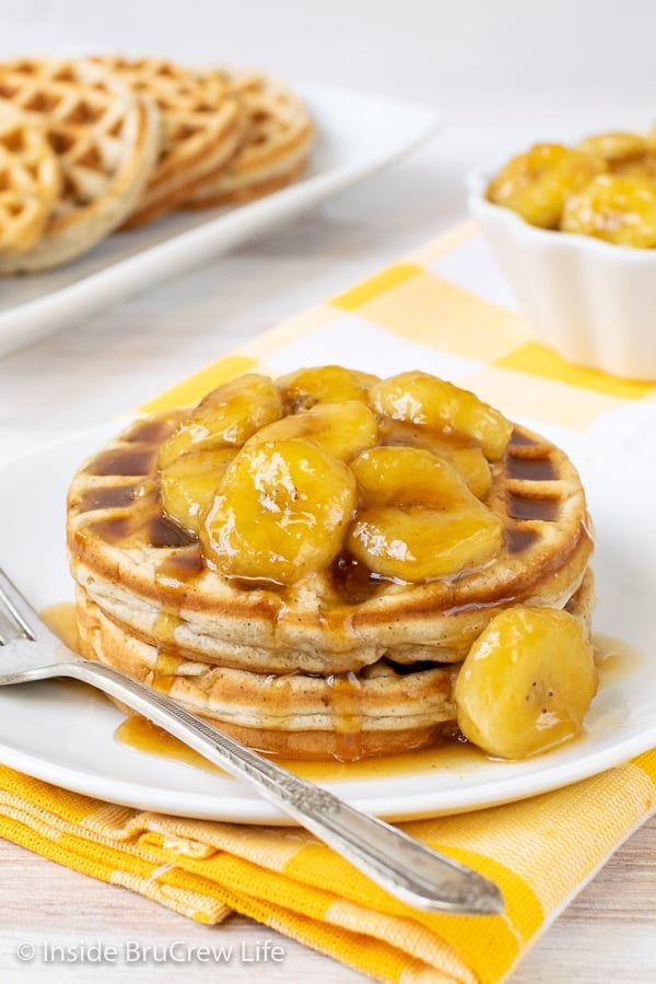 Two banana waffles on a white plate with caramelized bananas on top