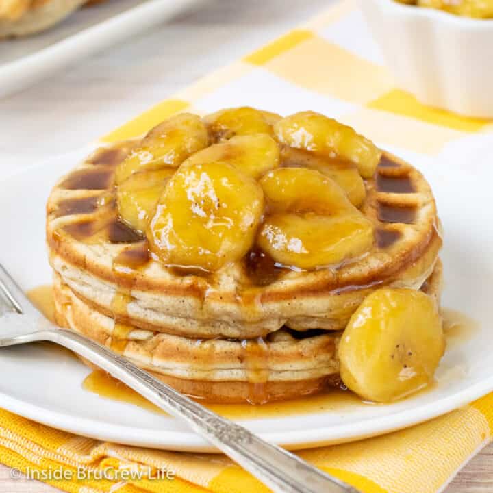 A white plate with two homemade banana waffles and banana slices on it