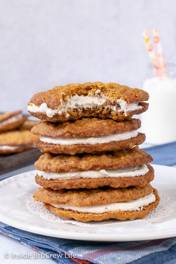 A white plate with four oatmeal cream pies stacked on top of each other.
