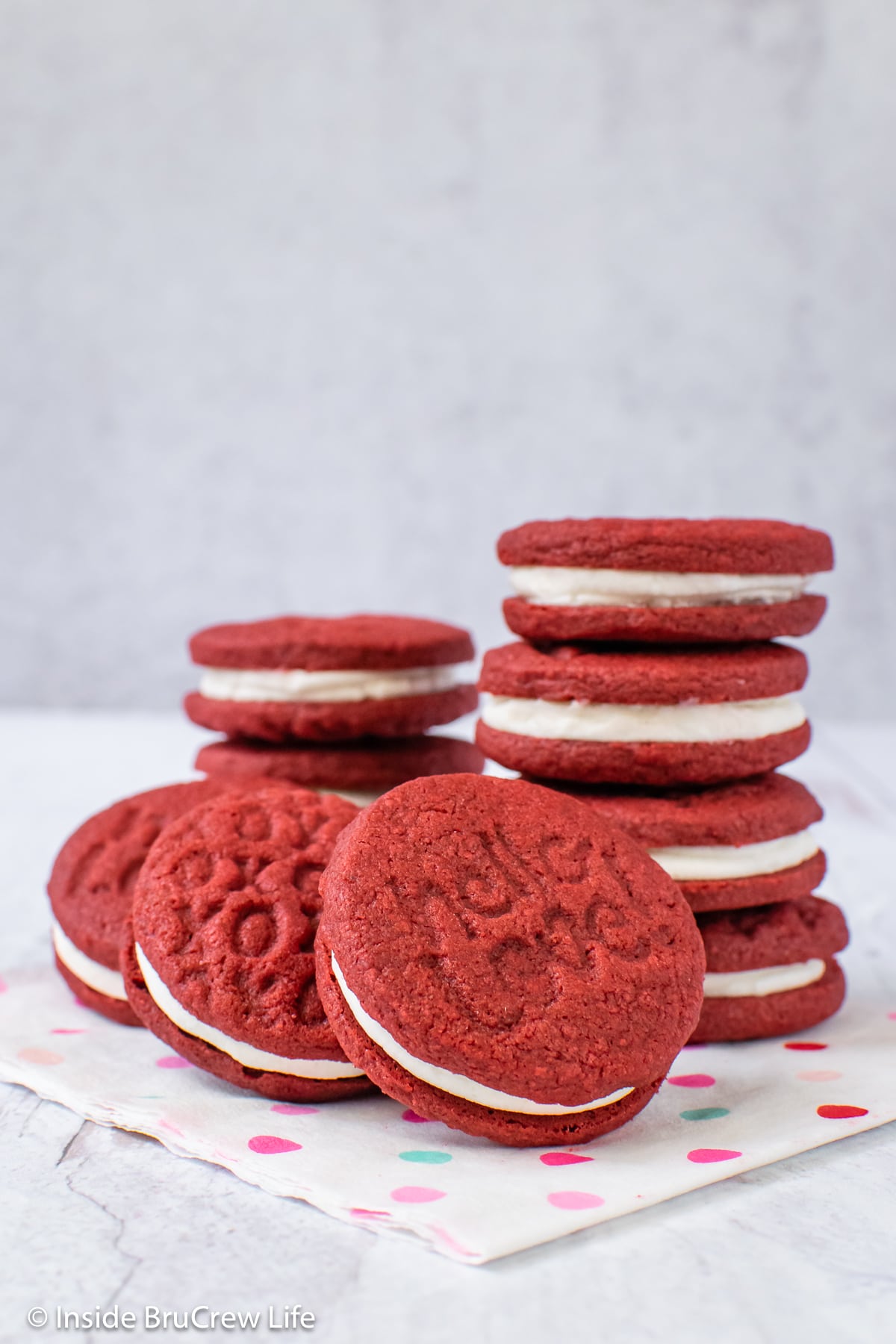 A pile of red sandwich cookies on a white napkin.
