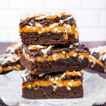 Three salted caramel brownies stacked together on a white plate.