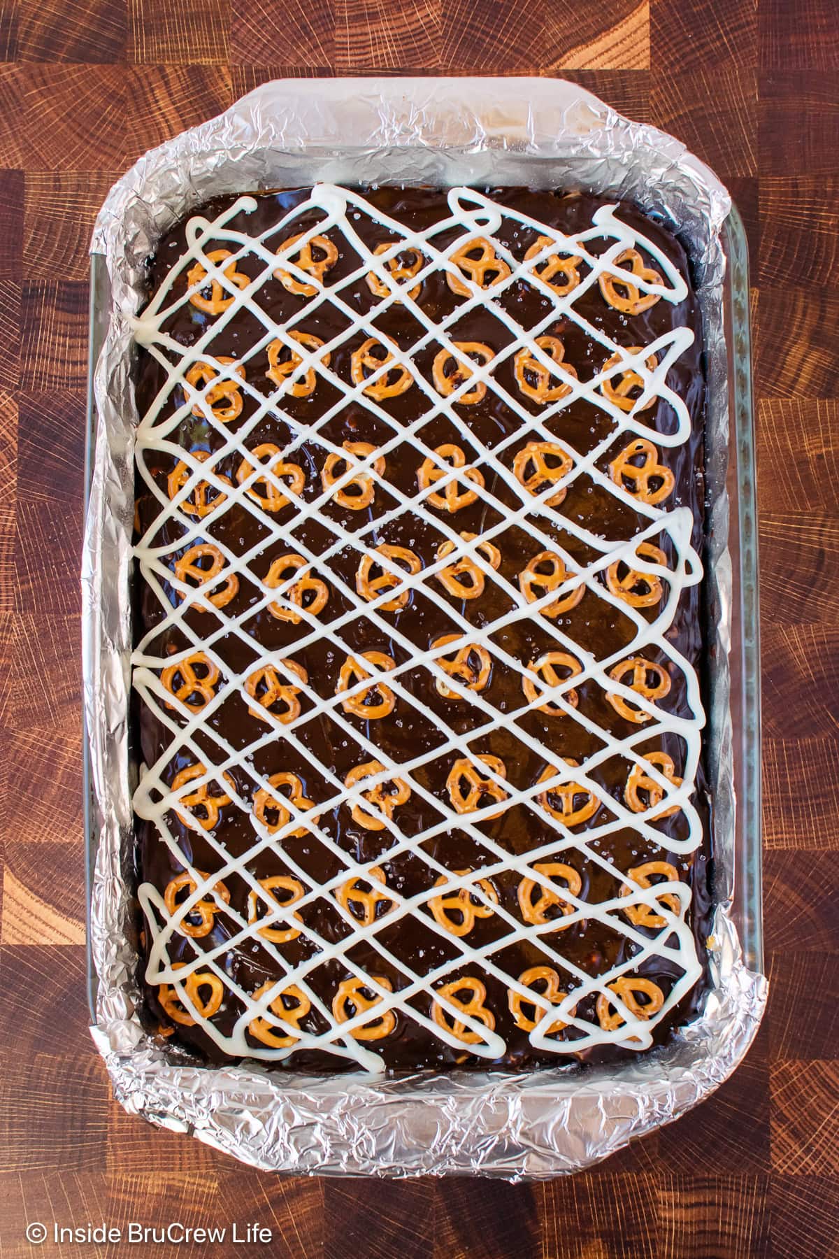 A pan of brownies topped with chocolate and pretzels.