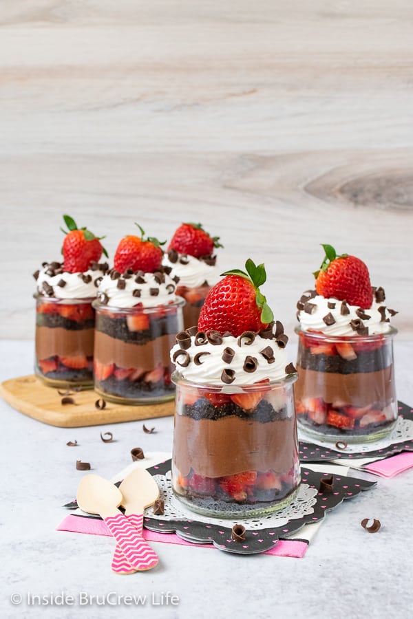 Jars of chocolate strawberry parfaits with Cool Whip, chocolate curls, and strawberries on top