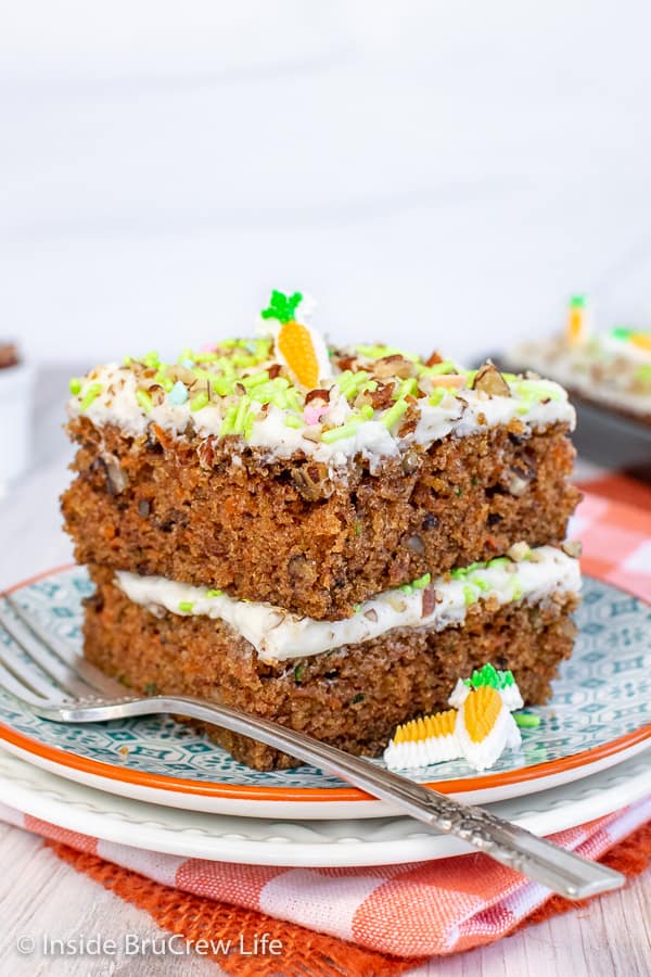 A stack of two carrot cake bars with sprinkles and nuts on a white and teal plate.