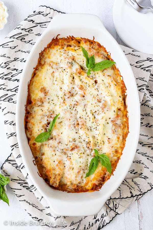 Overhead picture of baked stuffed shells covered in melted cheese in a white casserole dish.