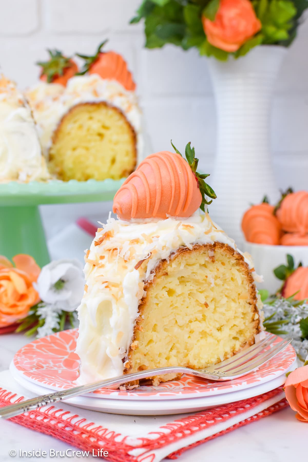 An orange plate with a slice of cake with frosting on it.