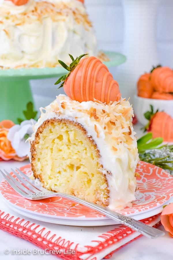 Coconut bundt cake topped with white frosting and toasted coconut on a peach colored plate.