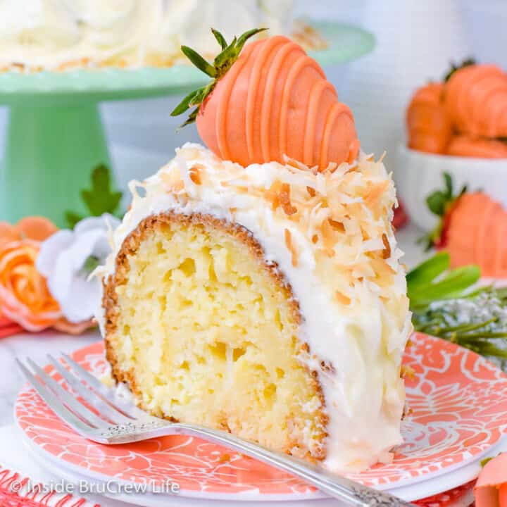 Coconut bundt cake topped with white coconut frosting and toasted coconut on a peach colored plate.