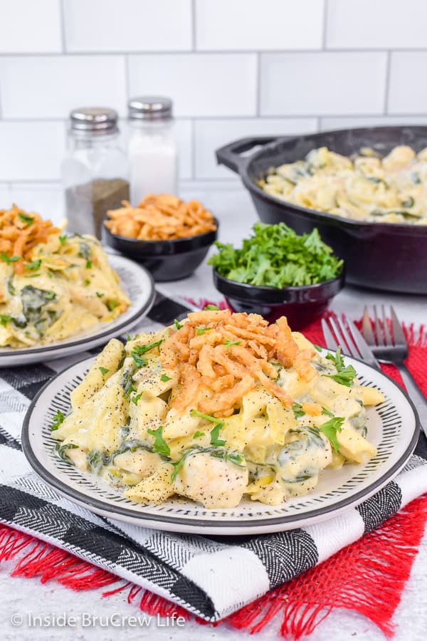 A white plate on a black and white towel filled with a creamy chicken pasta