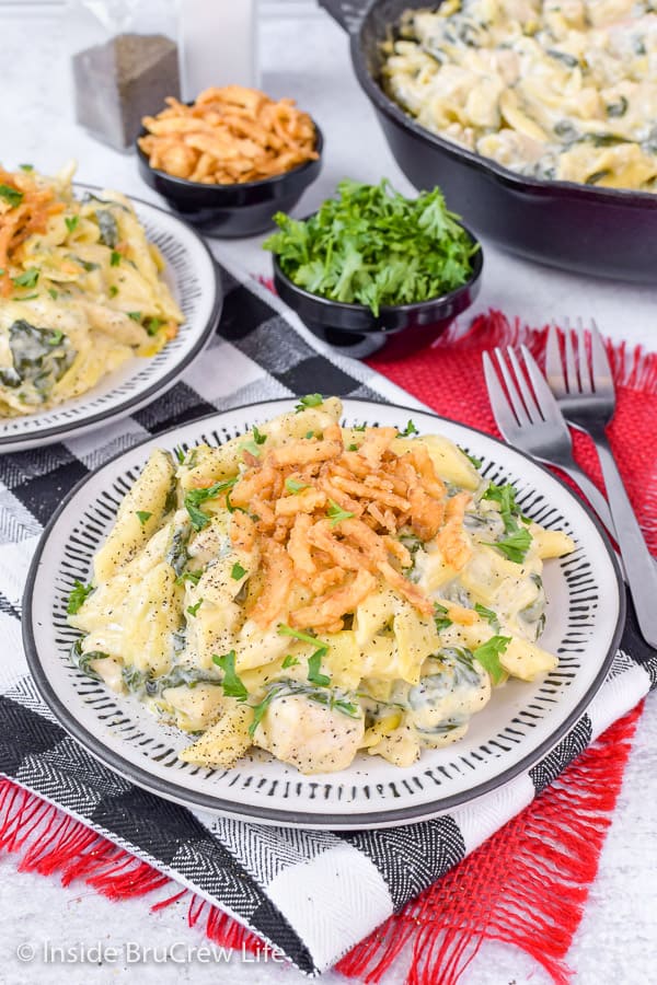 A white plate with the chicken pasta on it topped with crispy onions