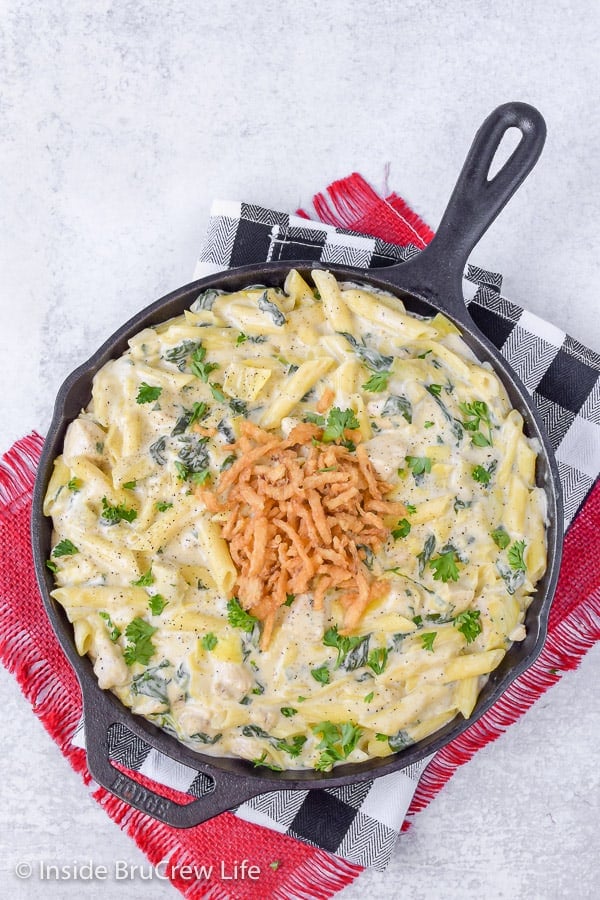 An overhead picture of a black skillet full of chicken pasta in a creamy cheese sauce