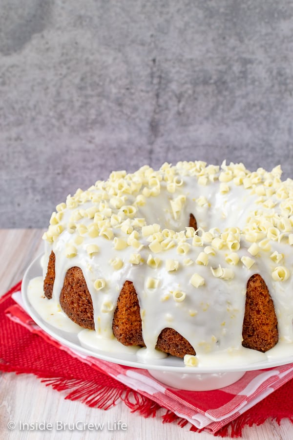 A close up picture of a lemon bundt cake with lemon glaze on a white plate