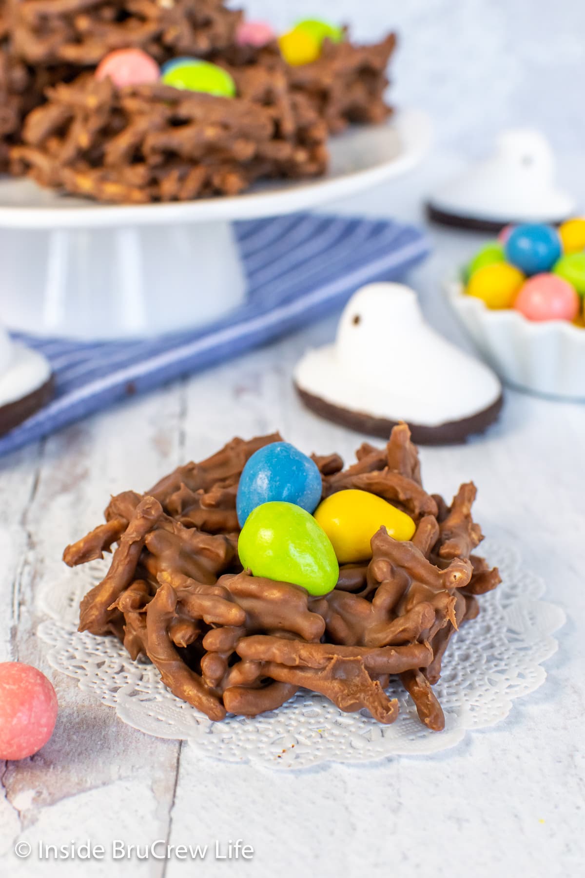 A chocolate nest cookie with candy eggs on a white board.