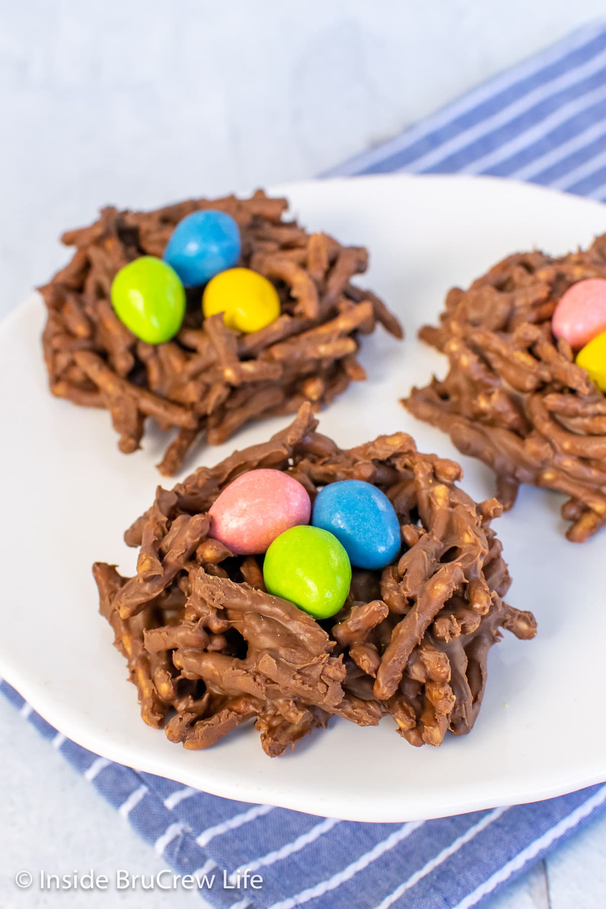 A white plate with nest cookies filled with candies.