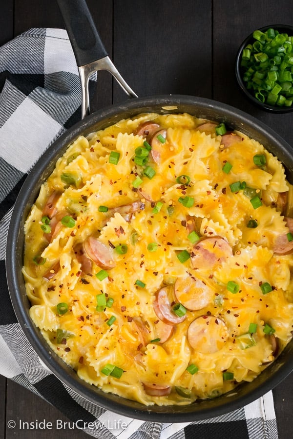 Overhead picture of a skillet full of cheesy pasta on a brown board