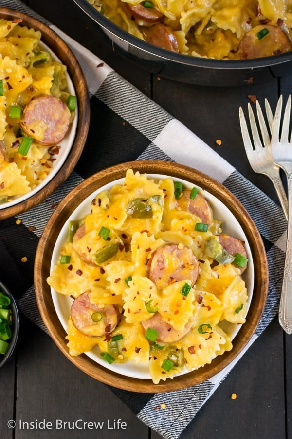 Overhead picture of a white plate inside a brown plate filled with cheesy pasta