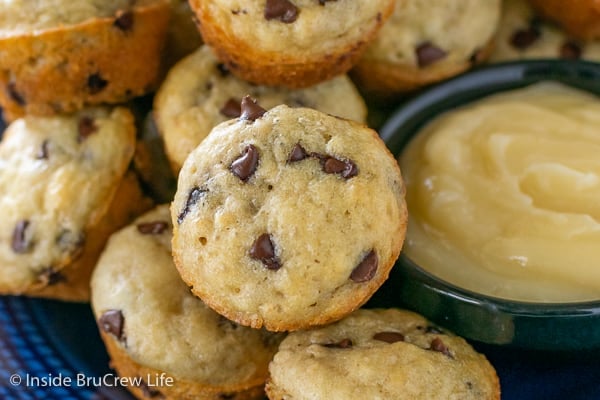 A close up picture of a mini chocolate chip pancake muffin beside a bowl of honey butter