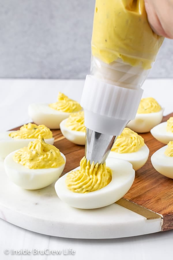 A picture of a piping bag filling the center of hard boiled egg halves
