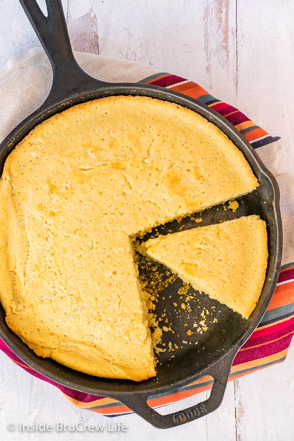 Overhead close up picture of a cast iron skillet with easy cornbread with a wedge cut in it