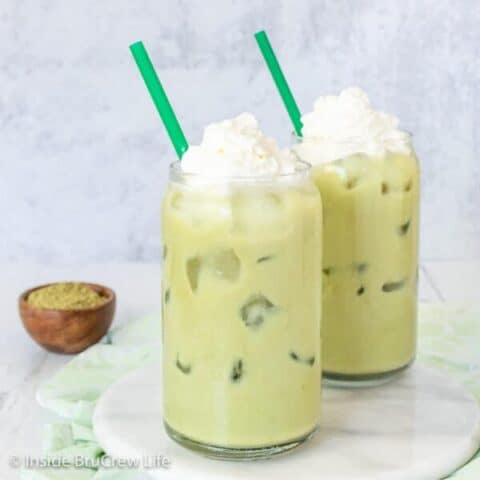 Two clear glasses filled with iced matcha and a green straw.