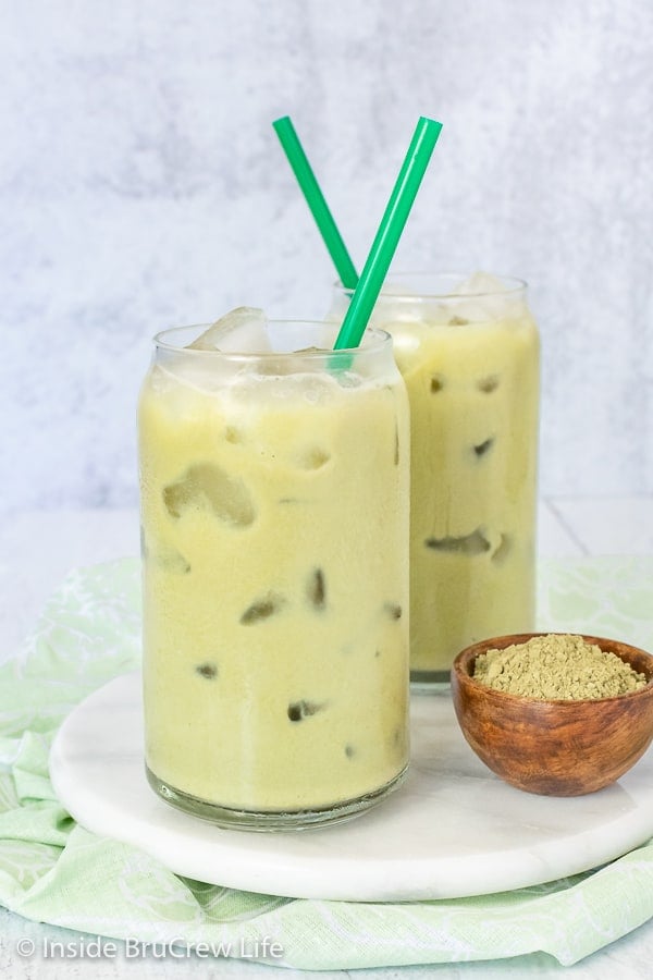 Two glasses filled with iced green tea on a white plate.