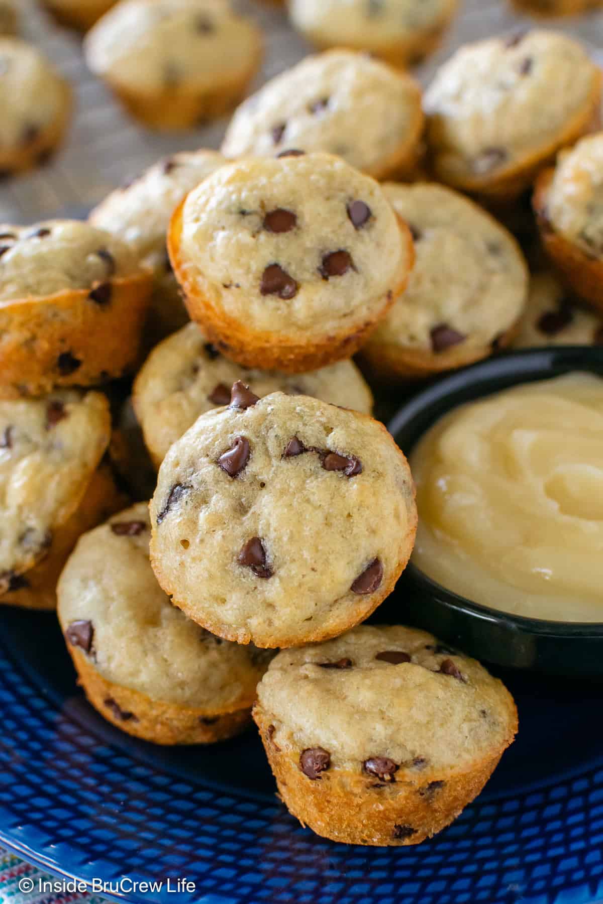 Mini chocolate chip pancake muffins and honey butter on a blue plate.