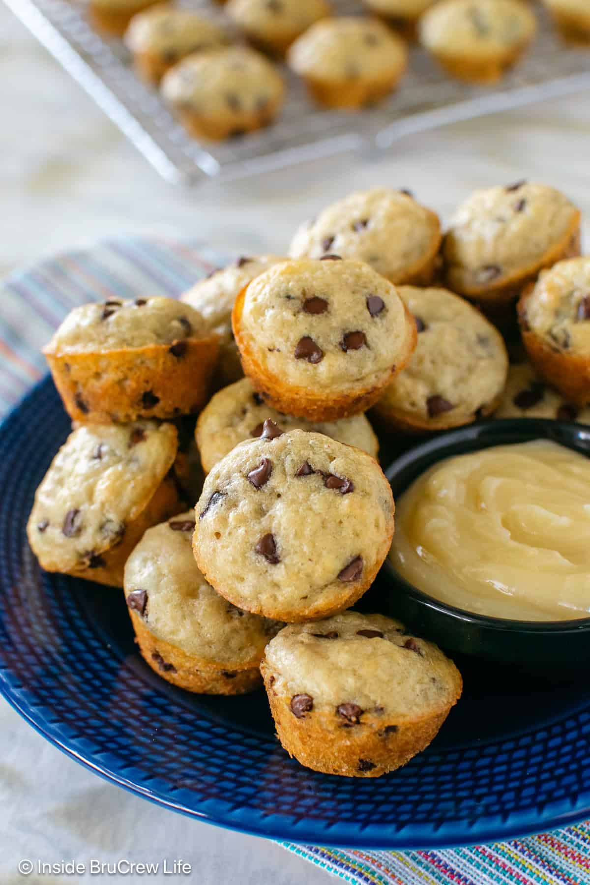 A batch of pancake muffins and a bowl of honey butter on a plate.