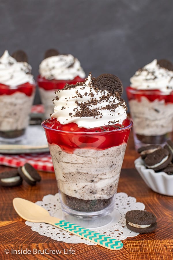 A No Bake Cherry Cookies and Cream Cheesecake Parfait on a white doily with a few parfaits behind it