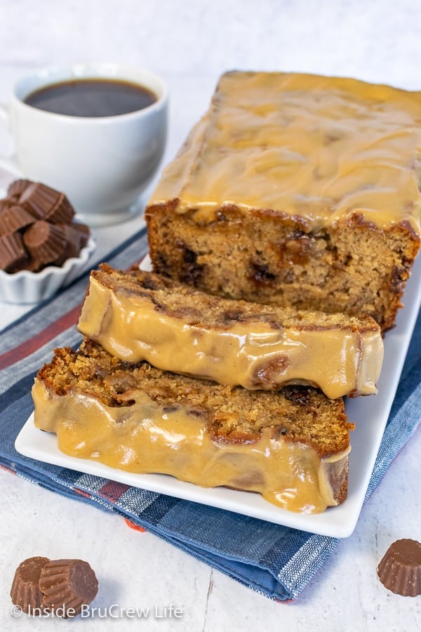 Slices of peanut butter cup banana bread with a peanut butter glaze falling forward on a white plate