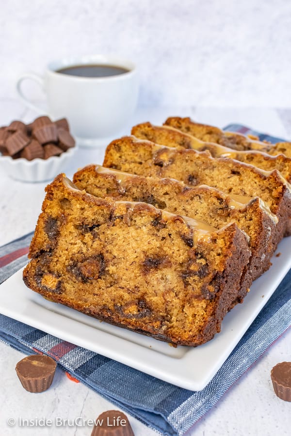 Close up picture of peanut butter cup banana bread slices on a white plate with a cup of coffee behind it