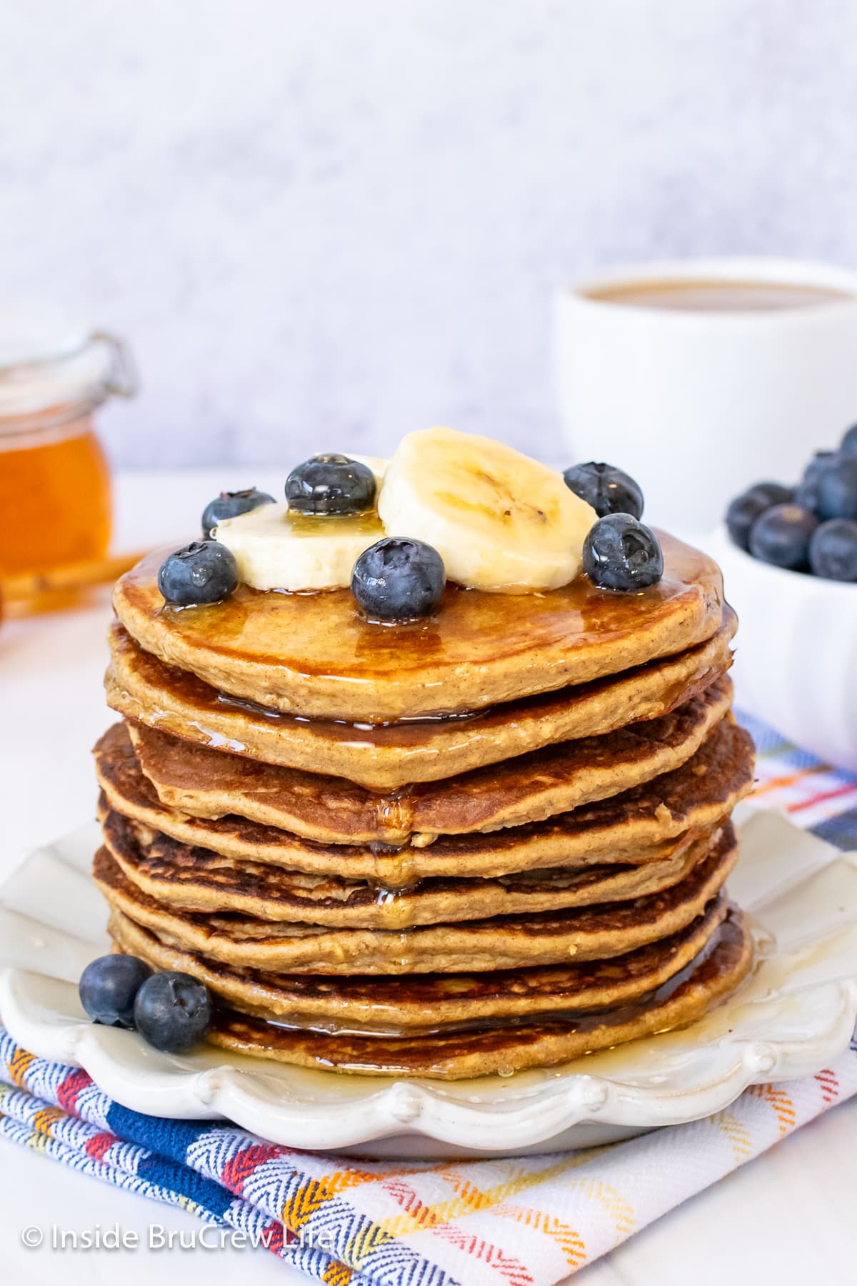 A large stack of banana pancakes topped with blueberries.