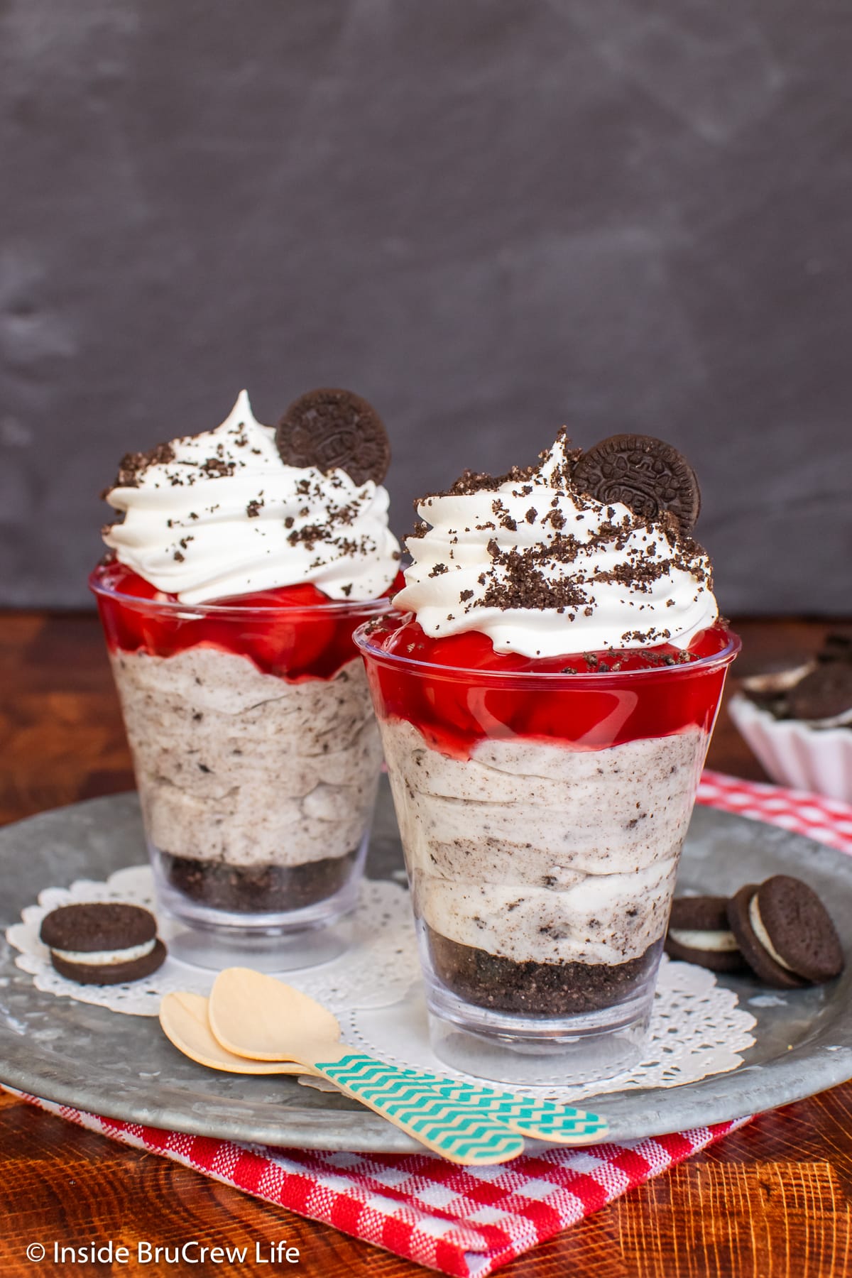 Two small cherry cheesecake parfaits on a tray.
